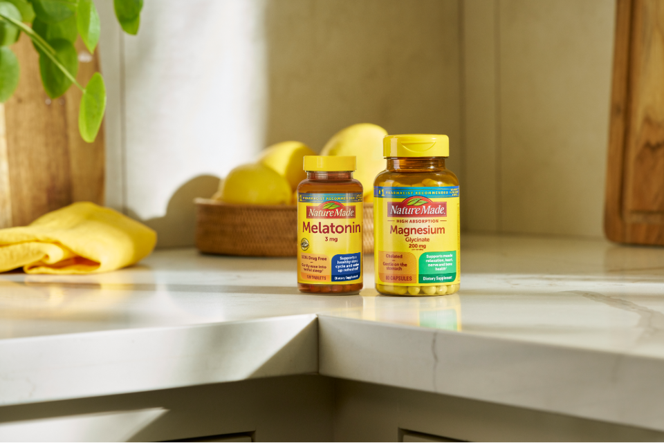Nature Made melatonin and magnesium supplement bottles on a kitchen counter with lemons.
