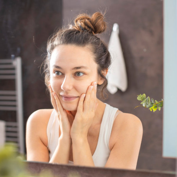 Woman touching her face in front of a mirror